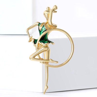 Gold green enamel gymnast with hoop brooch on white blocks