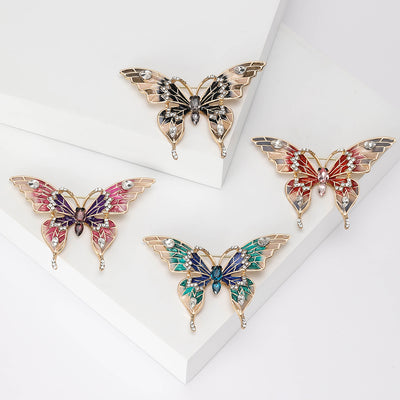Gray Butterfly, Red Butterfly, Purple Butterfly, Blue Butterfly brooch styles arranged on a light display