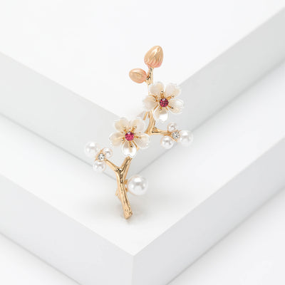 Gold plum blossom branch brooch with pearl and enamel flowers on white display