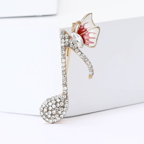 Red enamel wing gold music note brooch close-up on white