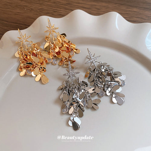 Layered gold-tone stars and reflective disc tassels arranged for a close front view.
