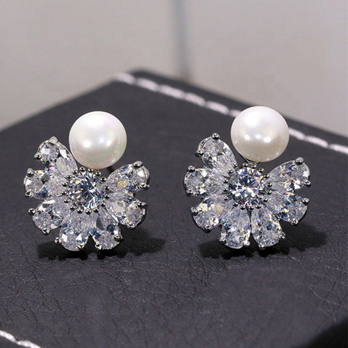 Pair of pearl flower crystal studs angled on black leather surface