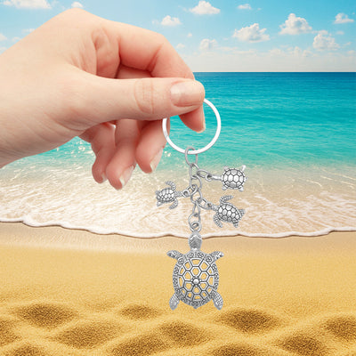 Sea turtle family keychain held against beach ocean backdrop