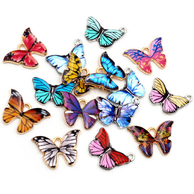 Front overview of colorful enamel butterfly charms with gold tone edges arranged on a light background