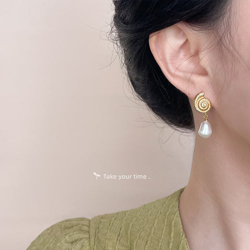 Spiral shell pearl drop earring worn on ear profile