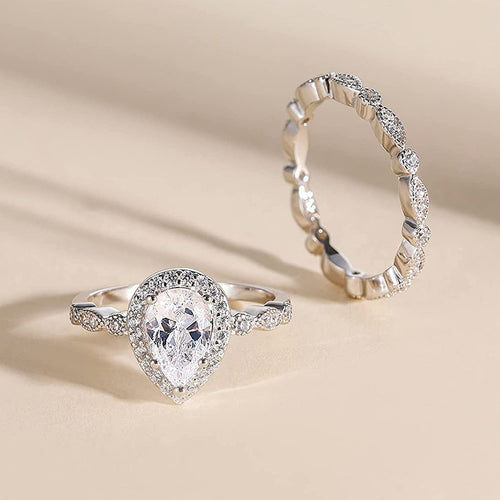 Pear halo and marquise band set standing on beige surface with shadows
