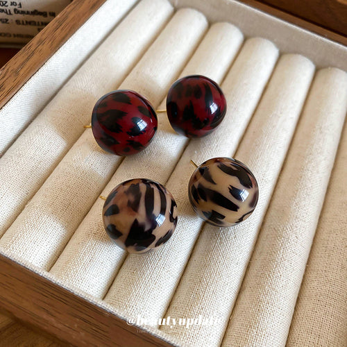 红黑斑驳纹圆形耳钉 in a styled close-up view