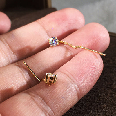 Gold round CZ threader bar drop earrings held in open palm