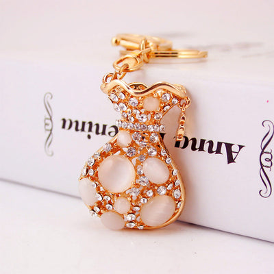 Front view of the pink-stone money bag charm resting against a book.