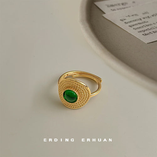 Gold green cabochon open ring on beige table with papers