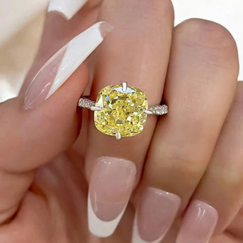 Yellow cushion solitaire ring worn on a hand