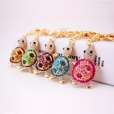 Five gold-tone turtle keychains with pink, blue, purple, green, and brown rhinestone shells.