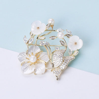 Front view of a pale shell-flower wreath with pearl buds and a small butterfly
