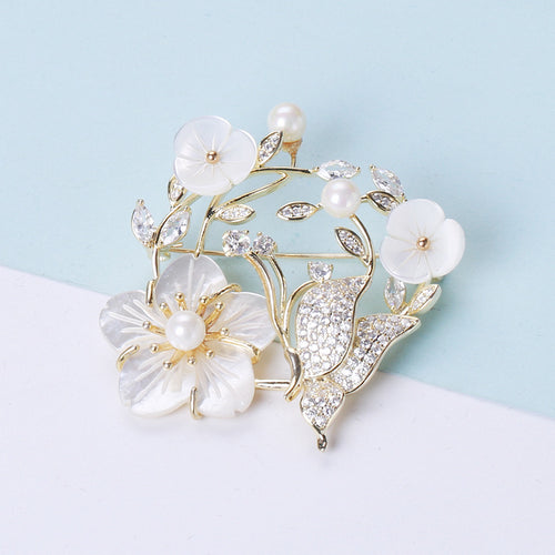 Front view of a pale shell-flower wreath with pearl buds and a small butterfly