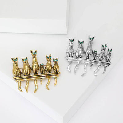 Gold and silver six-cat fence brooches with green crystal eyes