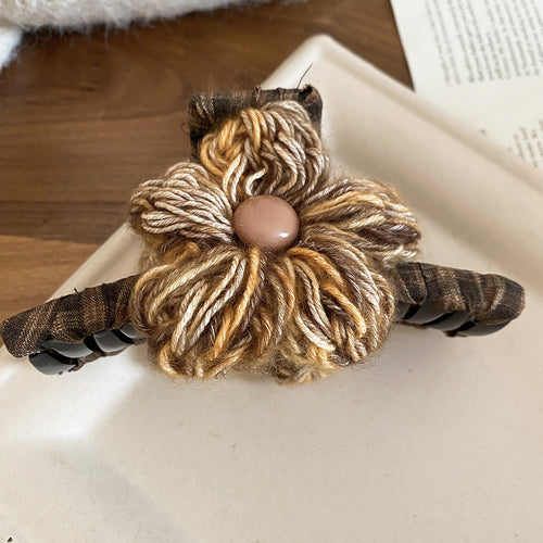 Coffee multicolor yarn flower claw clip with fabric-wrapped arms on tray