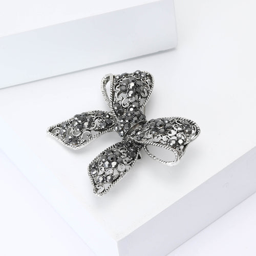 Black crystal bow brooch angled three-quarter on white display