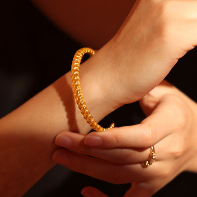 Gold twisted rope open cuff worn on wrist
