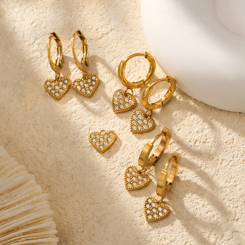 Assorted gold pave heart hoops and loose heart charms on sand