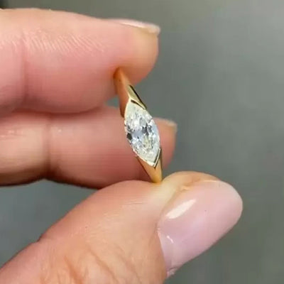 Product view showing gold-tone flush-set marquise clear solitaire ring
