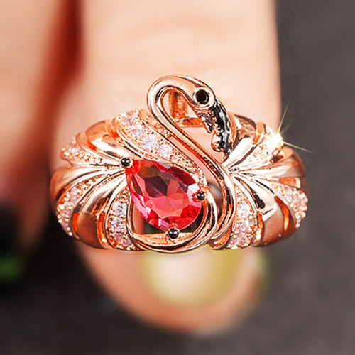 Close-up of rose gold swan ring held near fingertips
