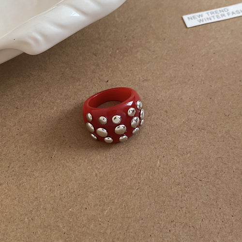 Red resin chunky ring with silver metal studs on cork surface