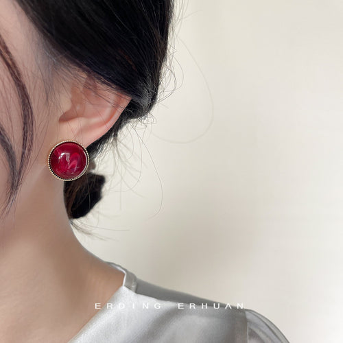Red resin round stud earring worn on ear profile