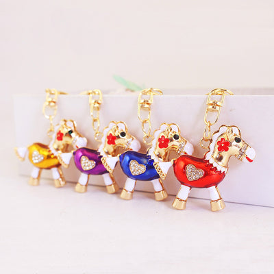 Four gold-tone horse keychains with gold, purple, blue, and red bodies displayed in a row.