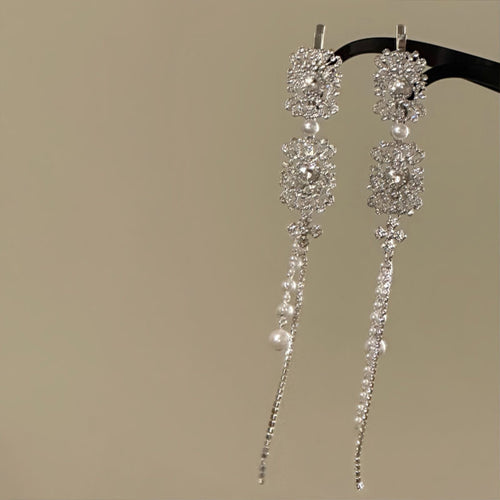 Pair of silver square rhinestone pearl tassel hair clips hanging on black bar
