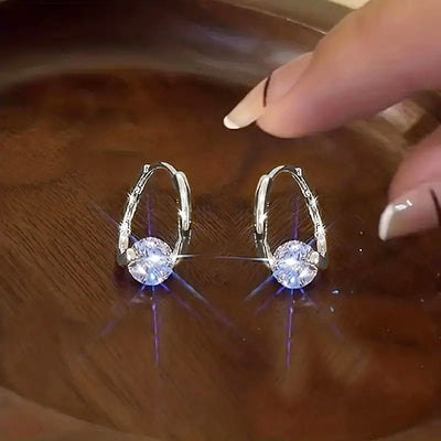 Product view showing faceted round clear stones suspended from slim leverback hooks