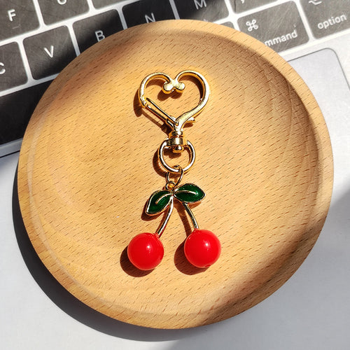 Bright red twin cherry keychain with two green leaves and gold heart clasp