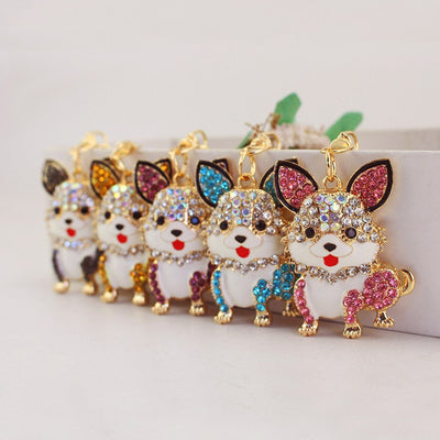 Five rhinestone corgi keychains in pink, blue, purple, gold, and gray are arranged in a row.