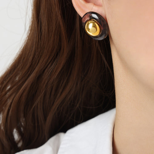 Smoke gray resin round stud with gold dome worn on ear