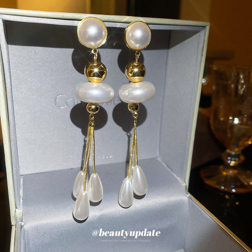 Product close-up of 金色珍珠水滴流苏耳环 showing stacked white pearls and gold-tone beads above three white teardrop tassels