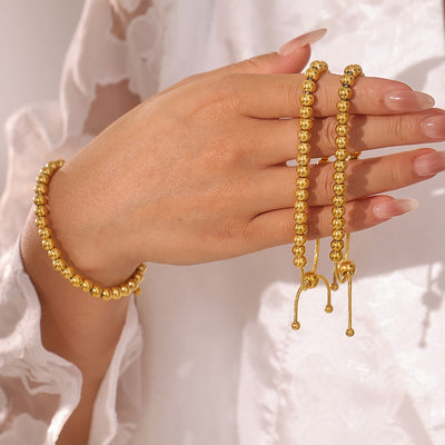 Gold bead bracelets worn and held in hand showing pull-cords