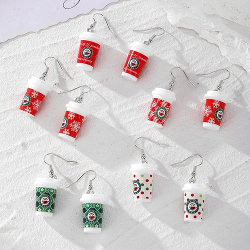 Five pairs of mini coffee cup earrings in red green and polka patterns on white fabric