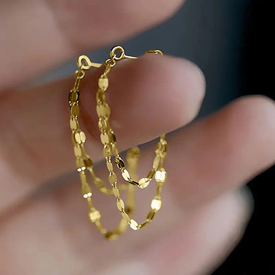 Gold double layer chain loop stud earrings held between fingers