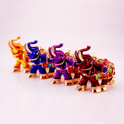 Four elephant keychains in gold, blue, purple, and red arranged diagonally.