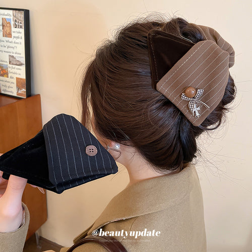 Brown pinstripe triangle claw worn in bun; black one held in hand