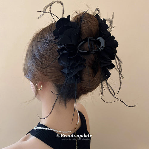 fabric petal flower hair claw with black feather fringe in red or black shown worn in a styled second view