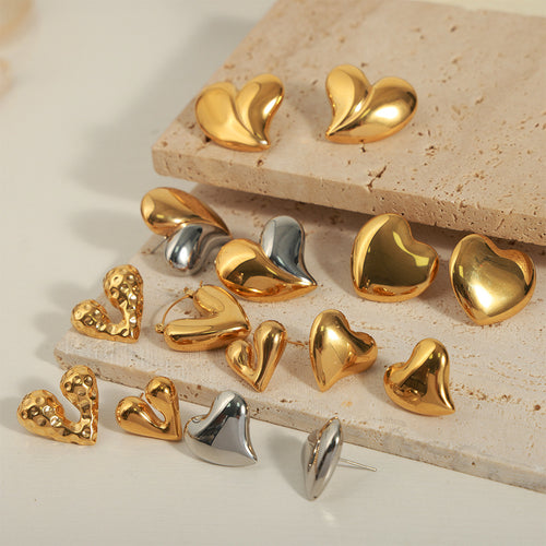 Assorted gold and steel heart earrings on stone slabs