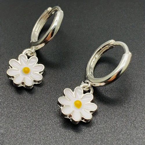 Close-up of white yellow enamel daisy charms on silver huggie hoops