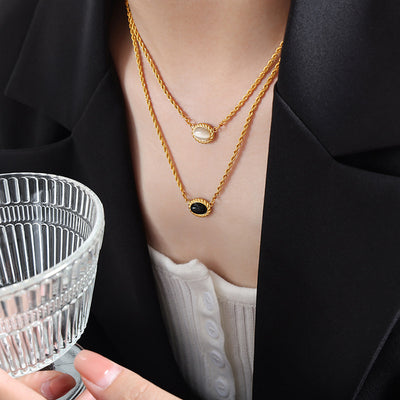 Model wearing gold double twisted rope necklace black and cream ovals