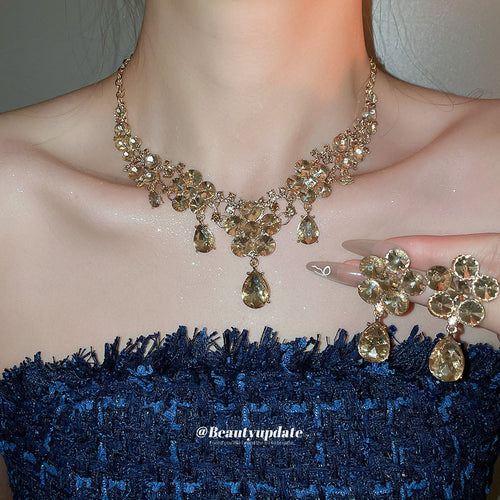 Gold champagne crystal flower necklace worn with matching drop earrings held