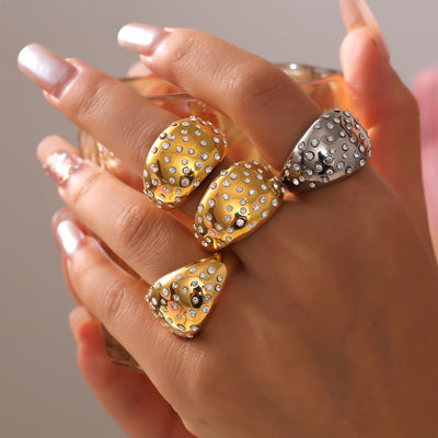 Hand wearing stacked gold and steel crystal pave dome statement rings