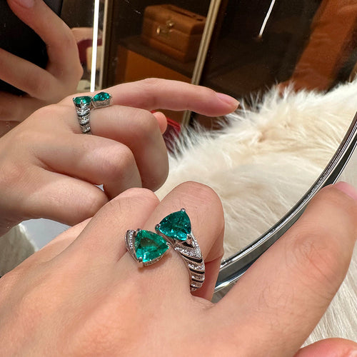 Silver open dual pear green crystal bypass ring worn on finger near mirror