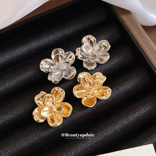 Layered sculptural flower studs in polished silver-tone and gold-tone finishes, display view