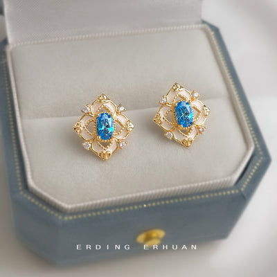 Gold-tone geometric-halo blue-oval-stone studs in the first product display.