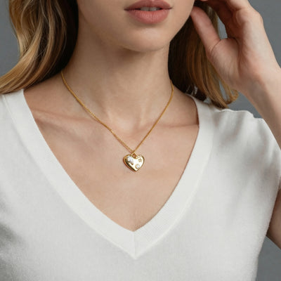 Gold heart zircon pendant necklace worn with hand at neck
