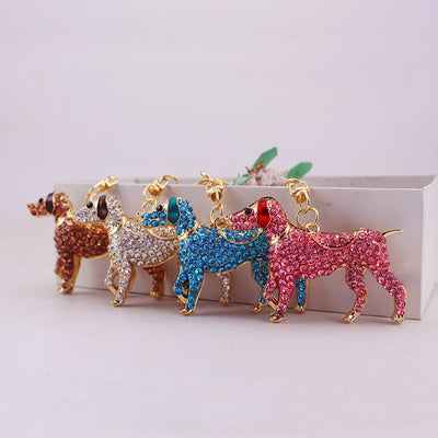 Four brown, white, blue, and pink rhinestone dog charms arranged in front of a box.